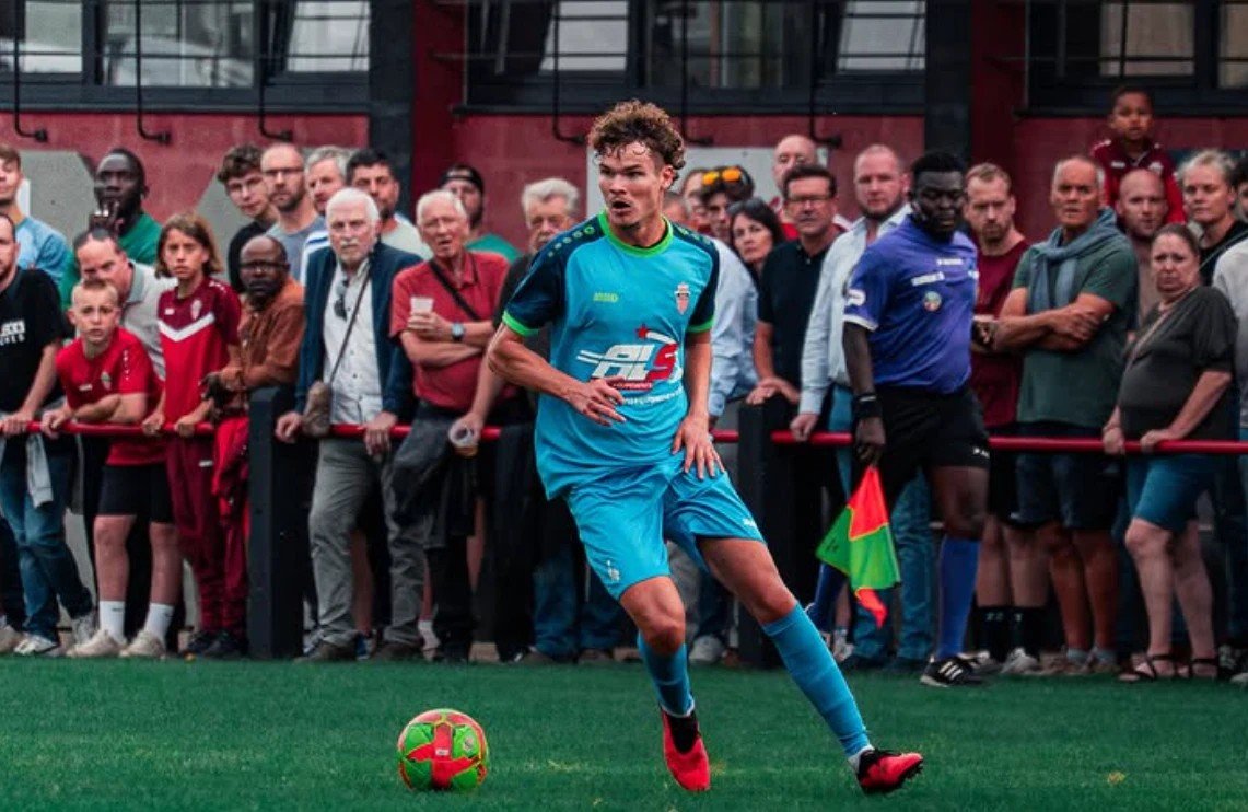Joueur en bleu ciel conduisant le ballon devant le public massé le long de la main courante