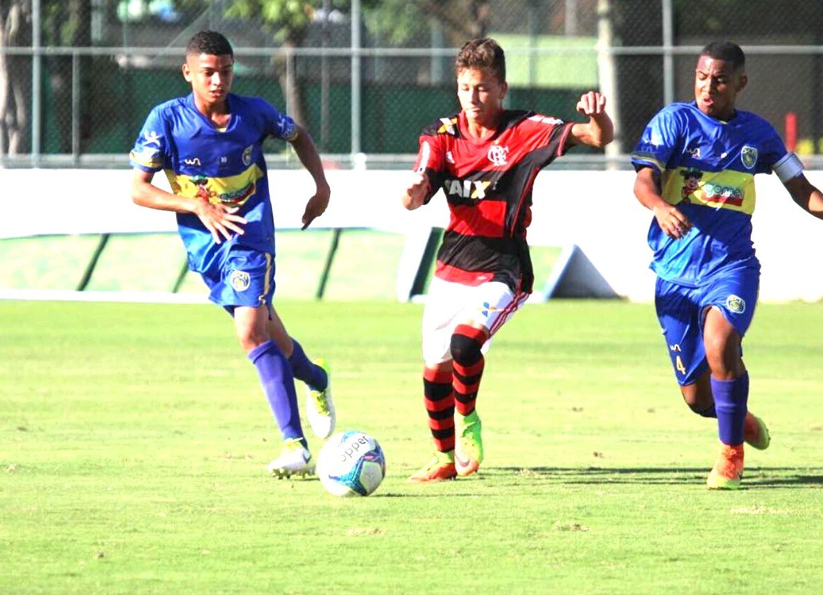 Zé Thiago, jeune, balle au pied sous le maillot de Flamengo face à deux défenseurs